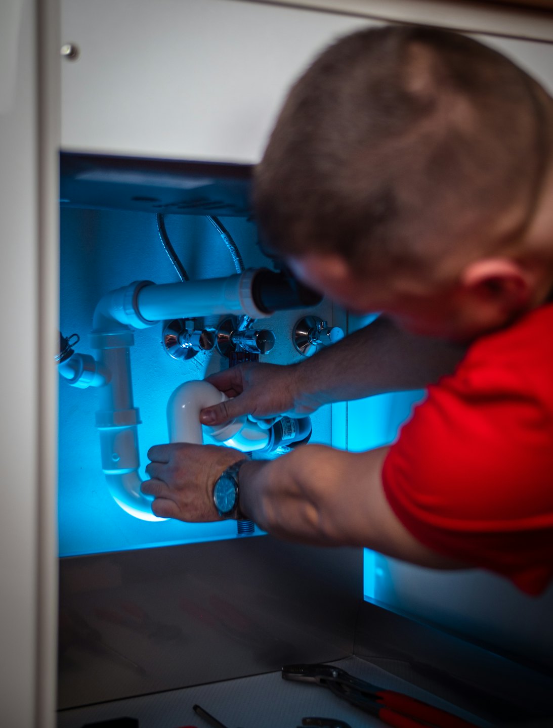 Techniker arbeitet an PVC-Rohren unter einer Spüle.